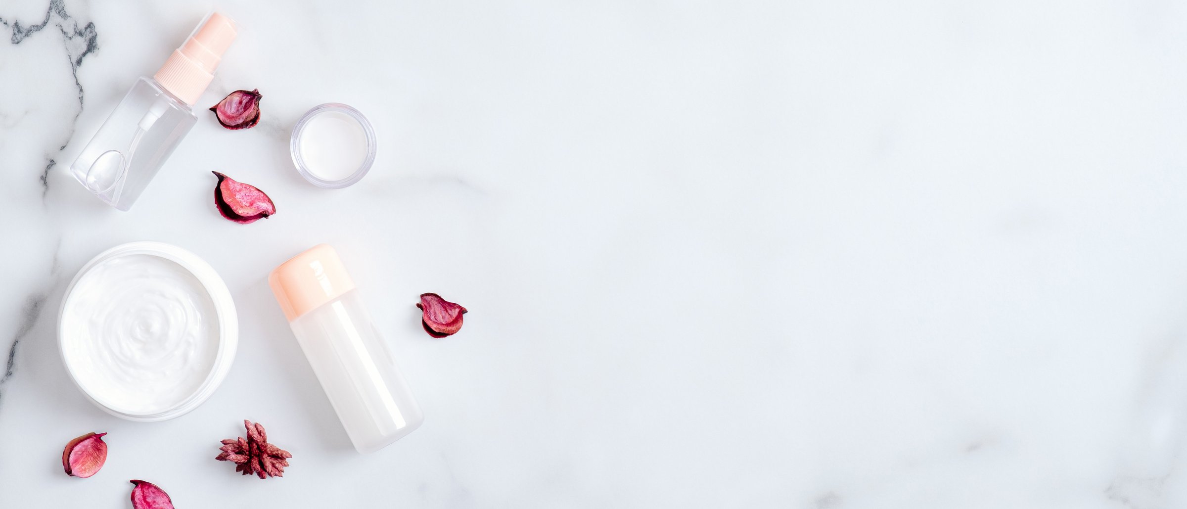 Skincare Products with Rose Petals on Marble Background